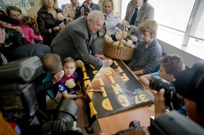 Marian Dziędziel rysuje na plakacie uśmiech