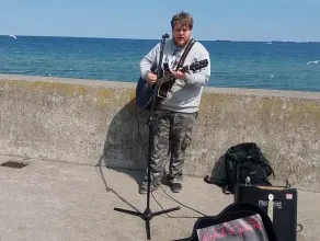 Wojtek z gitarą gra na bulwarze nadmorskim w Gdyni Hallelujah po Angielsku 