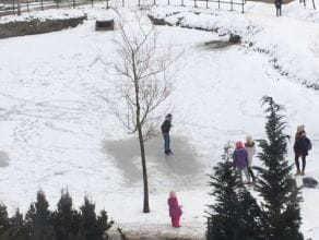 Dzieci ślizgają się na lodzie na oczku wodnym