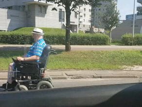 Inwalida w wózku elektrycznym jedzie ulicą