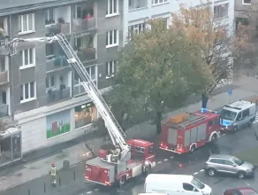Strażacy wchodza do mieszkania oknem