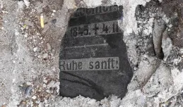Płyta nagrobna ukryta w murku przy ruchliwej ulicy