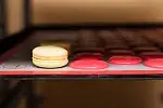Gotowy macarons z masą cytrynową (ang. lemon custard) obok suszących się ciasteczek. 