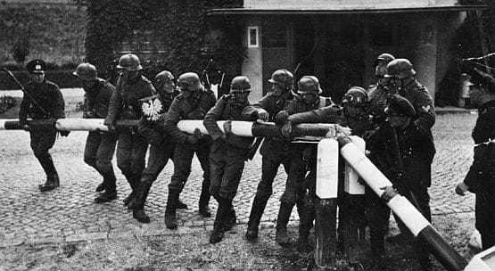 Niemieccy żołnierze wyłamują szlaban na przejściu granicznym w Kolibkach. Wykonane w połowie września 1939 r. miało rzekomo obrazować triumfalny pochód Wermachtu 1 dnia wojny.