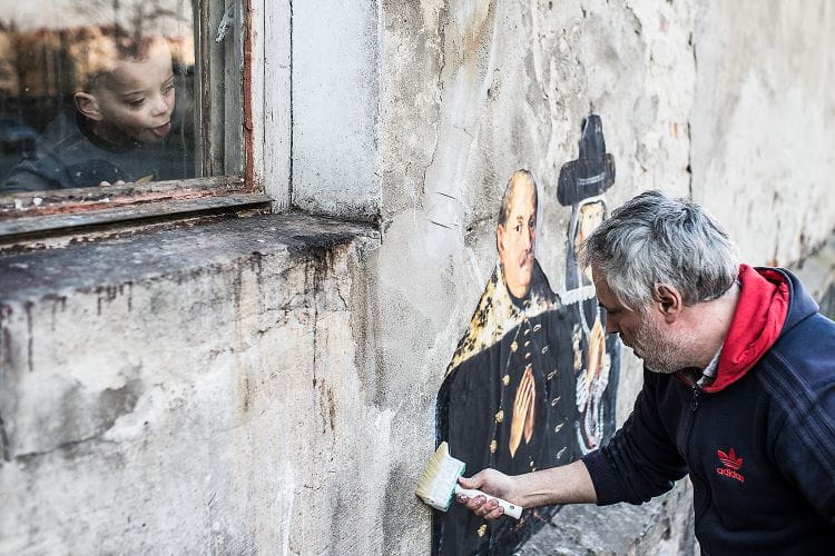 Julien de Casabianca przy pracy. Artysta nakleja fragment obrazu na murze domu na Dolnym Mieście w Gdańsku.