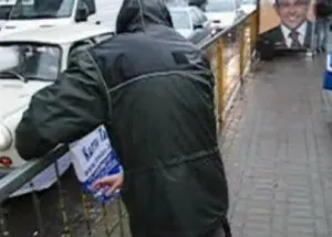 Młody mężczyzna został sfilmowany w czasie zawieszania plakatu na ogrodzeniu przystanku tramwajowego.