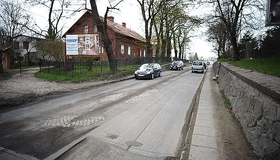 Fragment ul. Świętokrzyskiej ze zdartym asfaltem na wysokości skrzyżowania z ul. Wielkopolską.