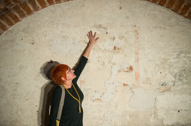 Dr Katarzyna Darecka pokazuje fresk z Jezusem na ścianie komory Palowej Ratusza Głównego Miasta.