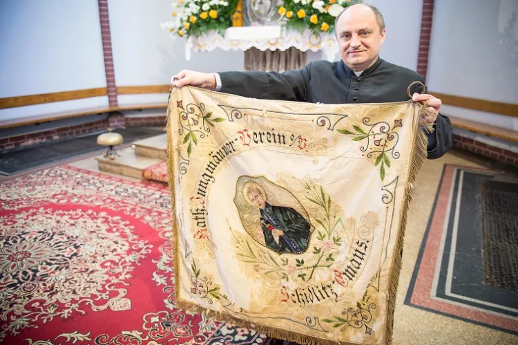 Ks. Jacek Tabor, proboszcz Parafii Rzymskokatolickiej pw. św. Franciszka z Asyżu w Gdańsku, prezentuje przedwojenny sztandar.