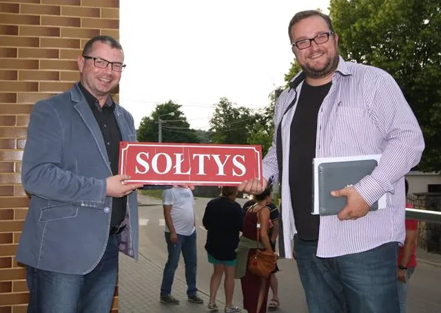 Świeżo upieczony sołtys Pręgowa, Marcin Dawidowski (z prawej) odbiera tabliczkę z napisem "Sołtys" z rąk Marka Golińskiego, zastępcy wójta gminy Kolbudy. 