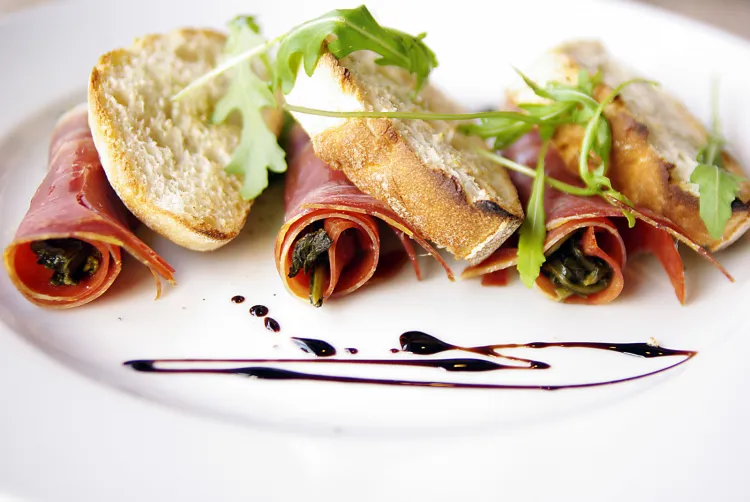 Friarielli Parma, czyli liście brokułu owinięte szynką parmeńską, podane z ciabattą i oliwą.