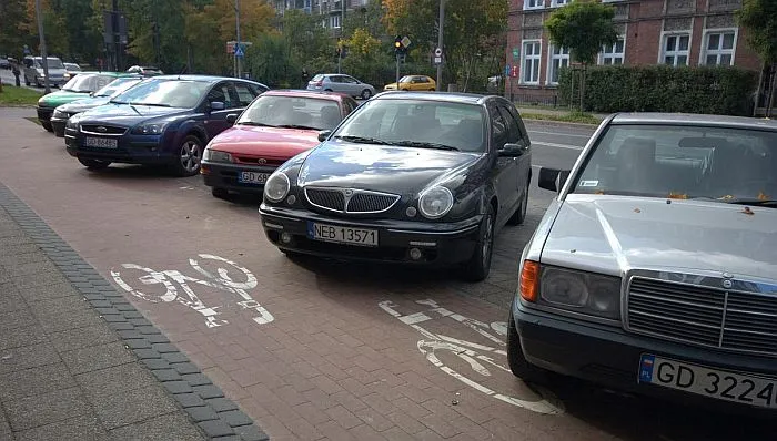 Samochody beztrosko parkują na ścieżce rowerowej, zagrażając bezpieczeństwu korzystających z niej rowerzystów.