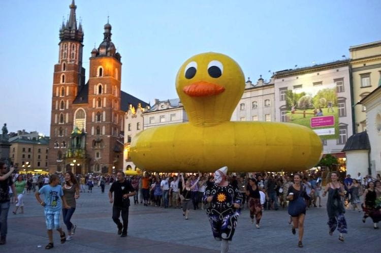 Włoski komik Leo Bassi rozrusza widownię, używając widzów do transportu swojej gigantycznej żółtej kaczki ulicami Dolnego Miasta.