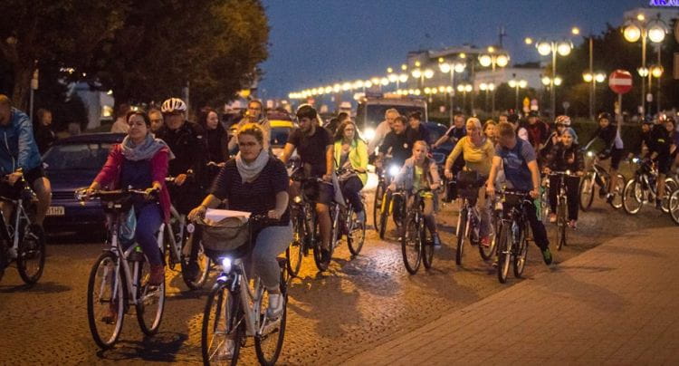 Nocny przejazd rowerowy skupia rowerzystów w różnym wieku.