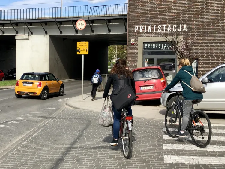 Ulica szybka i tłoczna, więc mieszkańcy na hulajnogach i rowerach wybierają chodnik. Samochody na przejściu dla pieszych i na zieleńcu utrudniają ruch.