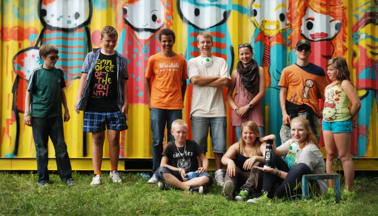 Stik z młodzieżą na tle muralu z mniejszego kontenera, którą wykonali wspólnie w 2011 roku.