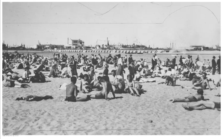 Plażowicze podczas wypoczynku na plaży w Gdyni, w tle port