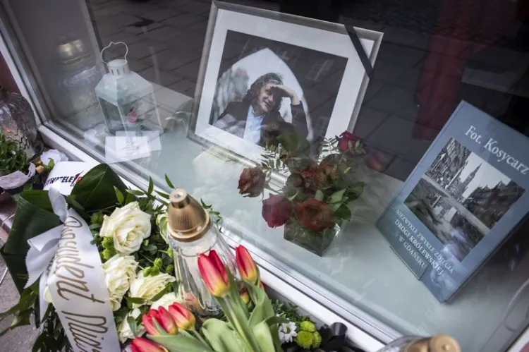 Wiązanki kwiatów i znicze upamiętniające zmarłego Macieja Kosycarza w oknie galerii, którą prowadził przy ul. Ogarnej w Gdańsku.