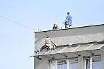 Robotnicy wykonujący drobne prace remontowe na dachu.
