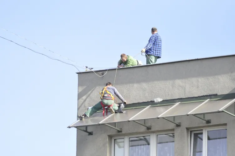 Robotnicy wykonujący drobne prace remontowe na dachu.