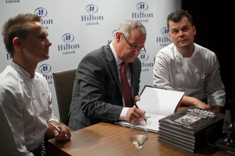 Marek Kondrat i szefowie kuchni hotelu Hilton podpisują książkę "Odkrywanie smaku".
