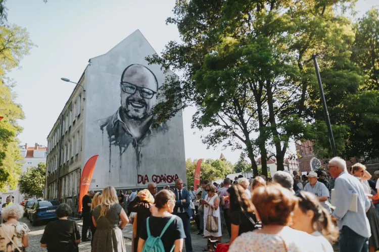 Odsłonięcie muralu Pawła Adamowicza. Na zdjęciu widać, że tylko ściana szczytowa jest wyremontowana. Od frontu budynek wciąż ma zniszczoną elewację.   