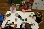 Podczas zajęć dzieci pod okiem nauczycieli tworzą pompony do czapek.