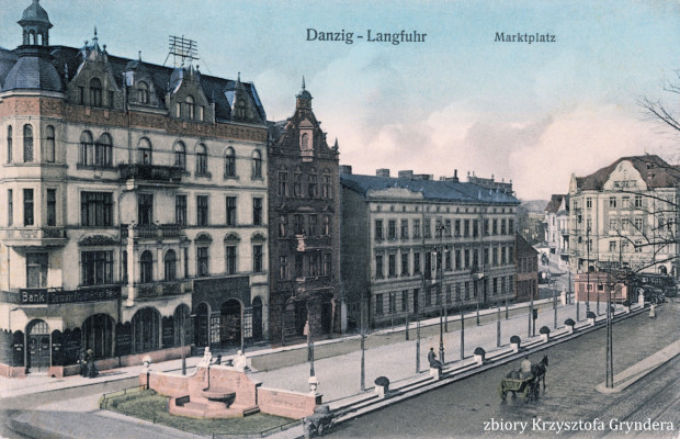 Zachodnia strona wrzeszczańskiego rynku (Marktplatz) po ukończonej w 1909 r. przebudowie na pocztówce wydanej ok. 1913 r. U dołu, po lewej, skrzyżowanie z Jäschkentaler Weg (ul. Jaśkowa Dolina), po prawej - wylot Mirchauer Weg (ul. Partyzantów). Na tyłach widocznych tu kamienic (częściowo zburzonych w 1945 r.) w latach 70. odbywały się Targi "Społem". W 1990 r. zaś postawiono tam pawilony handlowe "Manhattanu", dziś w prezentowanym tu miejscu stoi centrum handlowe o tej samej nazwie.