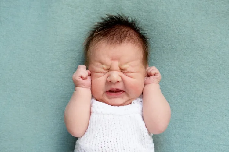 Napadowy, silny i trudny do ukojenia płacz niemowlęcia, wzdęty i napięty brzuch, zaciskanie piąstek i naprężanie się podczas płaczu to jedne z objawów kolki u niemowląt. 