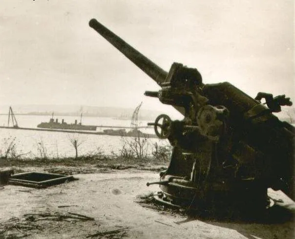 Jedna z dwóch armat baterii "Canet". Zdjęcie nieznanego autora, prawdopodobnie zrobione po kapitulacji w dniu 19 września 1939 r. W tle krążownik ORP "Bałtyk". Zdjęcie pochodzi z Wojskowego Biura Historycznego (dawne CAW). 