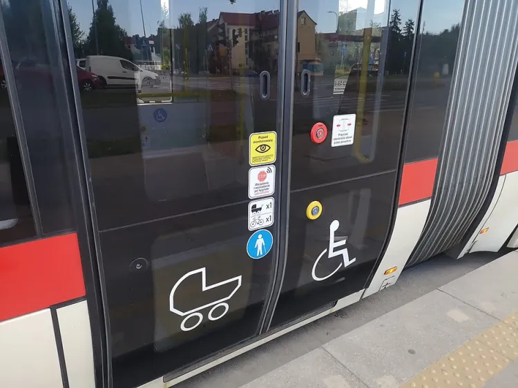 Naklejki informujące o limitach oraz miejscu dla pasażera na wózku inwalidzkim umieszczone na tramwaju.