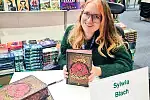 Sylwia Błach podpisuje książki podczas jednych z targów książki. 