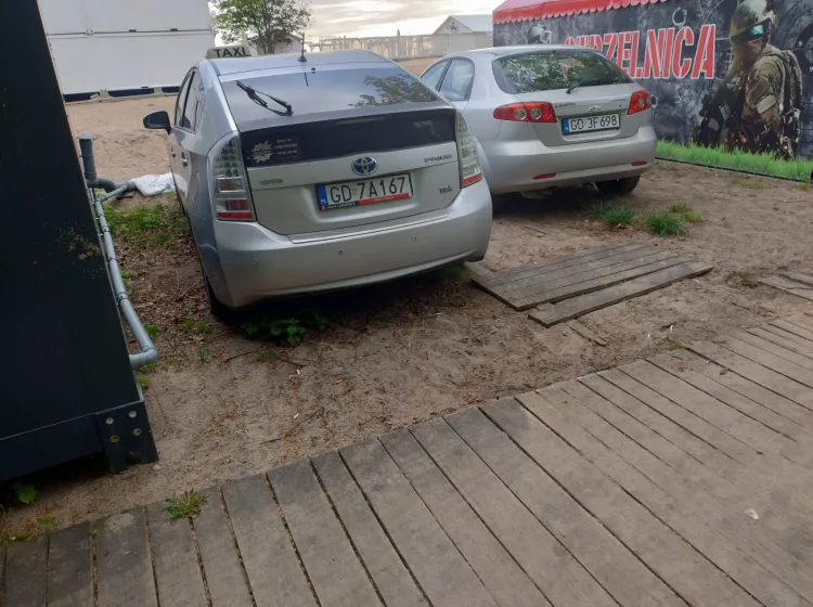 Samochody regularnie przejeżdżają przez drewniany podest oraz parkują między wejściami na plażę.